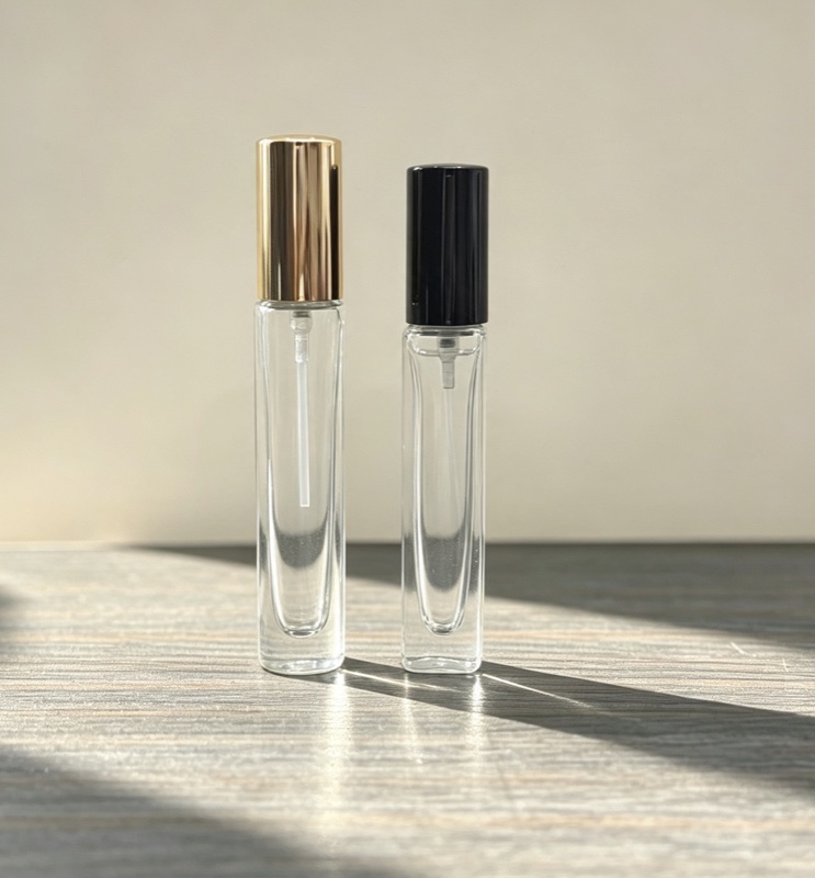 Slim rectangular glass perfume sprays with gold and black caps on a wooden table