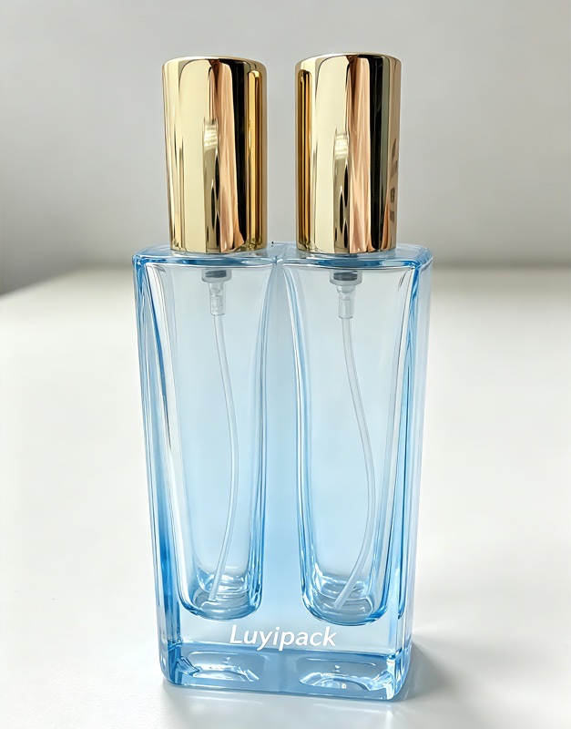 Blue twin-chamber glass perfume bottle with tall gold caps